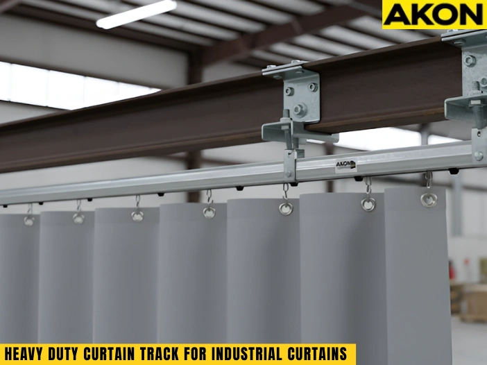 Heavy duty curtain track for industrial curtains mounted to steel I-beam in warehouse