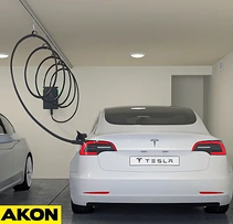EV charge cable held overhead by a trolley track above a white car in a garage